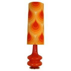 an orange table lamp with a red shade on it's base and a white background