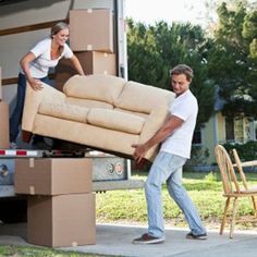 a man and woman unloading furniture from the back of a moving truck