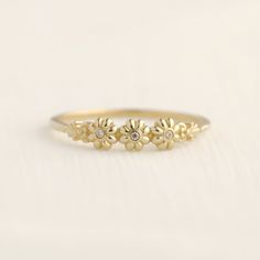 a yellow gold ring with three small flowers on the front and center, sitting on a white surface