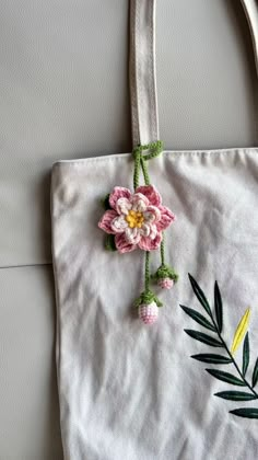 a white bag with pink flowers and green leaves hanging from it's side on a wall