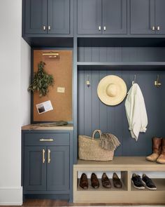 an entryway with blue cabinets, shoes and a hat hanging on the coat rack