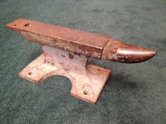 an old rusted metal object sitting on top of a green carpet covered floor next to a wall