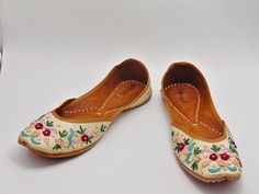 Ethnic Indian/Pakistani style shoes durable and hand stitched with genuine leather sole and leather padded cushion inside. These lovely pair of khussa have a base white raw silk fabric dotted with multi colored thread work in flower design. They offer comfort and style, while still looking fabulous in these. Perfect or brides or everyday outfits. We offer many different designs of shoes to choose from. See our page for more of our collection! We ship out in a timely matter, wrapped in care for a Festive Embroidered Leather Flats, Festive Slip-on Flats For Spring, Spring Festive Slip-on Flats, Festive Spring Slip-on Flats, Handwork Leather Flats For Festivals, Leather Flats With Dori Work For Festivals, Leather Flats With Handwork For Festivals, Bohemian Embroidered Closed Toe Flats, Traditional Meenakari Slip-on Flats