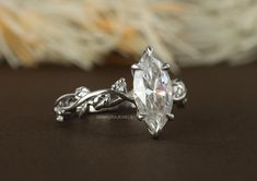 a close up view of a diamond ring on a brown surface with feathers in the background