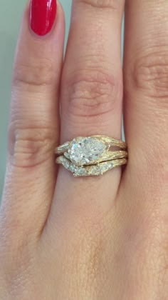 a woman's hand with two wedding rings on it and a red manicure