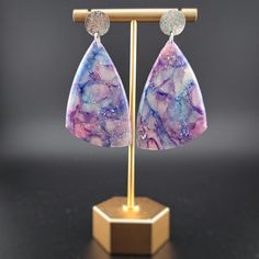 These translucent earrings are beautiful in any light, but they absolutely stun when graced by the sun. Threads of lavender, turquoise, and magenta dance through each piece. They are a great gift for anyone wanting to embrace their whimsical side with a touch of elegance! They are handmade and unique--no two have the same design. They are lightweight, which makes them a thoughtful gift for anyone who has trouble with heavier earrings. Each earring is made by hand and will have slight variations in the pattern. All of my materials are nickel-free and hypoallergenic. Reika means "wander" in Icelandic, and being a wanderer is crucial to my existence. As such, all of my pieces are imbued with parts of the natural world that have inspired me. It is my hope to provide this same inspiration to an Handmade Purple Drop Clip-on Earrings, Purple Resin Jewelry With Matching Earrings, Purple Resin Jewelry For Party, Purple Resin Party Jewelry, Purple Resin Drop Earrings, Unique Iridescent Earrings, Unique Iridescent Pierced Earrings, Hypoallergenic Purple Bohemian Earrings, Unique Iridescent Earrings For Party