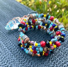 the multicolored beaded bracelet is sitting on top of a blue table cloth