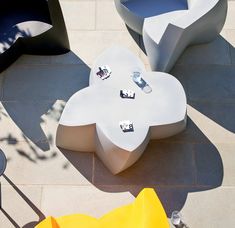 an outdoor seating area with various shapes and sizes on the ground, including two large flower shaped tables