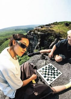 a man and woman playing chess on top of a mountain