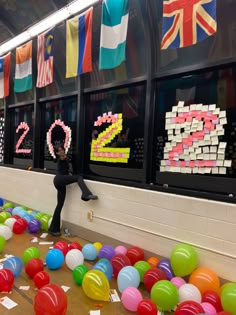 there is a man that is standing in front of some balloons and letters on the wall