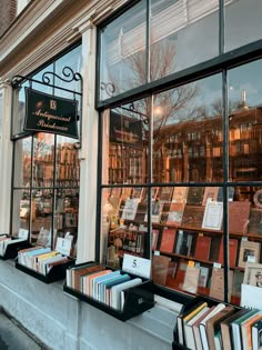 books are on display in the window of a book store with many books behind it