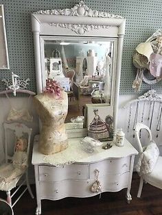 a white dresser sitting next to a chair in a room filled with dolls and other furniture