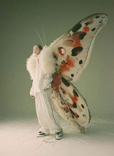 a woman standing next to a giant butterfly with spots on it's wings and legs