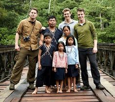 a group of people standing on top of a wooden bridge