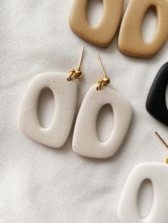 three pairs of white and black earrings sitting on top of a table next to each other