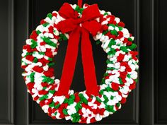 a christmas wreath with red, white and green sprinkles hanging on a black door