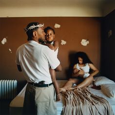 a man standing next to a woman on top of a bed in front of a wall