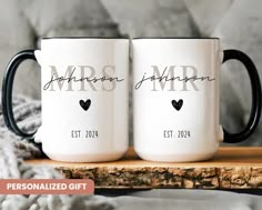 two personalized coffee mugs sitting on top of a wooden table next to a blanket