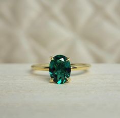 a green ring sitting on top of a wooden table next to a white cloth covered wall