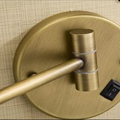 a close up of a metal object on a wall with a wooden stick in it