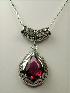 Simulated Red Ruby PendantBig Teardrop Design#P28This is a stunning Victorian inspired pendant necklace. This beautiful necklace is handcrafted from sterling silver. The flawless 6 carat man-made red ruby is a pear cut gemstone. Measurements are 16mm in length and 12mm in width. The 1.5mm sterling silver chain is 18" long (Chain may be different than pictured). The entire pendant is 1-11/16" long by 13/16" wide. The pendant & necklace are marked 925 for sterling silver. Notice the beautiful craf Fine Jewelry Ruby Teardrop, Ruby Drop Jewelry For Anniversary, Ruby Teardrop Fine Jewelry, Silver Pear-shaped Jewelry For Valentine's Day, Pear-shaped Silver Jewelry For Valentine's Day, Formal Ruby Drop Jewelry, Formal Ruby Drop Necklace, Formal Drop Ruby Necklaces, Elegant Pear-shaped Ruby Jewelry