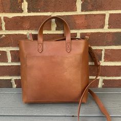 Timeless Crossbody Bag From Madewell! Features A Top Zip Closure, Top Carry Handles, Optional, Adjustable, Crossbody Strap, Outside Pocket, Interior Wall Pocket, Fully Lined, Flat Base For Stability, And Made From Vegetable-Tanned Leather That Wears Well Over Time. Approx: 11" W X 9 1/2" H X 3" D, With A 3 1/2" Strap Drop And A 20 1/2" - 24" Crossbody Strap Drop. Excellent Condition, With Minimal Marks/Creases To Leather Finish/Stain Throughout, Including A Darker Spot In Back, As Pictured. In English Saddle. Firm Price! Dark Tan Rectangular Bag With Adjustable Strap, Rectangular Dark Tan Bag With Adjustable Strap, Cognac Rectangular Satchel For Everyday, Rectangular Cognac Satchel For Everyday, Dark Tan Rectangular Satchel For Daily Use, Dark Tan Leather Bag For Everyday Use, Everyday Rectangular Cognac Satchel, Cognac Crossbody Bucket Bag For On-the-go, Dark Tan Rectangular Bag With Removable Pouch