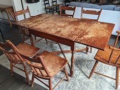 an old wooden table with six chairs and a rug on the floor in front of it