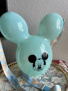 a blue mickey mouse head on top of a round tray with a ribbon around it