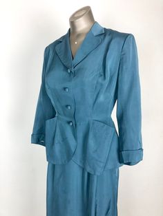 "1940's teal suit from Finland has a fitted jacket and a-line pencil skirt. The jacket has a rounded lapel, angular pockets at the hips, cuffed sleeves, and a button front with covered buttons. The jacket is tailored with shoulder pads, full white rayon completely hand stitched lining, double princess seams for fit, and lots of beautiful handwork including hand-stitched welt button holes. The skirt has pleating at the waist front waist, and single side pleat in the back. There's a metal side zip Vintage Blue Skirt Suit For Formal Occasions, Vintage Fitted Skirt Suit With Notch Lapel, Classic Fitted Skirt Suit With Pockets, Vintage Fitted Blue Suits, Blue Fitted Vintage Suit, Fitted Vintage Blue Suits, Spring Vintage Tailored Suits, Vintage Fitted Single Breasted Suit, Fitted Vintage Suits For Workwear