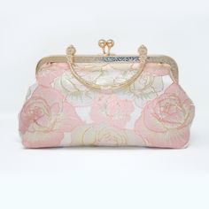 a pink and gold purse with flowers on the front, sitting against a white background