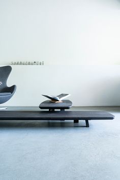 a modern living room with white walls and blue carpeted flooring, including a black coffee table that has a book on it