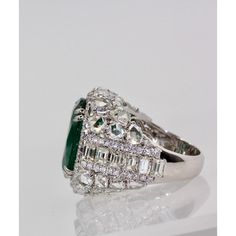 This is part of Chairish’s Fine Jewelry assortment.  Oval Emerald 12.25 Carat Diamond Surround 8.85 Carat Total Weight 21.10 Carat  This oval Emerald weights in at 12.25 carats and is a gorgeous Emerald Green with transparency. The Diamonds weigh in at 8.85 Carats and the mount is exceptional the Diamonds are VS1-VS2 and G-J in color. This is a bombe mount. The shoulders of the ring are embellished with baguette cut Diamonds in the center border with a perimeter of round cut Diamonds accents. Th Luxury Green Marquise Diamond Ring, Luxury Marquise Emerald Ring With Diamonds, Luxury Diamond Cluster Ring With Gemstones, Luxury Emerald Cluster Ring With Vvs Clarity, Luxury Marquise Emerald Ring, Luxury Pear-shaped Diamond Ring With 17 Jewels, Luxury Gia Certified Pear-shaped Rings, Luxury Gia Certified Pear-shaped Wedding Ring, Luxury Pear-shaped Gia Certified Rings