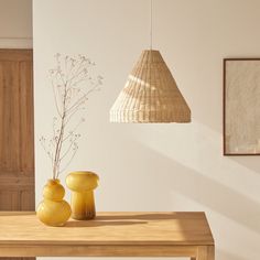 two yellow vases sitting on top of a wooden table next to a light fixture