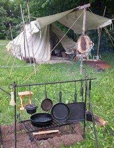 pots and pans are sitting on the grill in front of a teepee tent