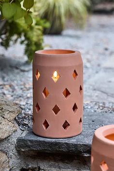 two pink vases sitting next to each other on a stone slab with plants in the background