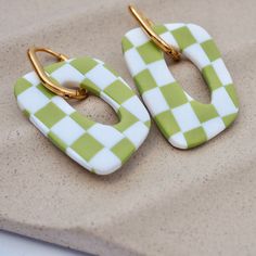 two green and white checkered earrings sitting on top of a table