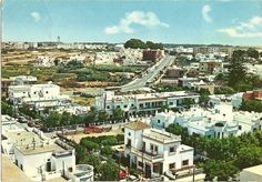 an aerial view of a city with lots of white buildings and trees in the foreground