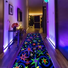 the hallway is lit up with purple lighting and stars on the carpet, along with potted plants