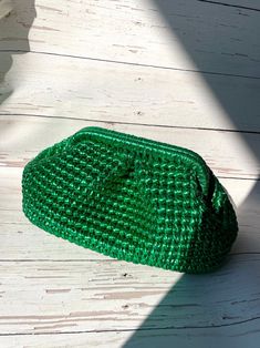 a green purse sitting on top of a white wooden floor next to a shadow cast wall