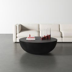 a white couch sitting next to a black table on top of a gray floor in front of a white wall