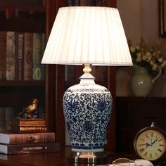 a blue and white lamp sitting on top of a table next to a book shelf