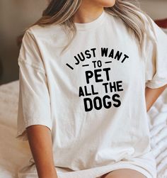 a woman sitting on a bed wearing a t - shirt that says i just want to pet all the dogs