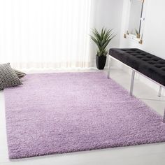 a living room with a purple rug on the floor and a black bench next to it