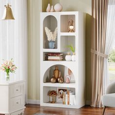 a living room with a white book shelf filled with lots of books and vases