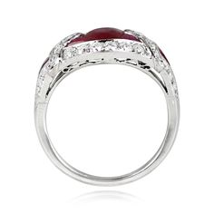 A gemstone ring centering a 1.08 carat oval cut natural ruby. French cut rubies set on either side of the center stone form a geometric design, which is accented by a halo of old European cut diamonds. A single French cut ruby and additional old European cut diamonds are set on each shoulder. The total weight of the additional diamonds is approximately 0.84 carats. The mounting is handcrafted in platinum, with openwork details on the under-gallery.
The measurements of this ring are approximately Oval Cabochon Ruby And Diamond Ring, Elegant Ruby Rings With Oval Cabochon Center Stone, Ruby Rings With Center Stone, Oval Cabochon Shape, Oval Ruby Ring With Platinum, Oval Ruby Ring With Platinum Band, Oval Ruby Ring With Platinum Setting, Oval Ruby Ring With Platinum Center Stone, Formal Oval Ruby Ring In Platinum, Polished Ruby Ring With Diamond In Round Cut