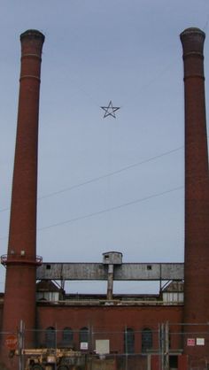 an industrial building with two large chimneys and a star shaped kite in the sky