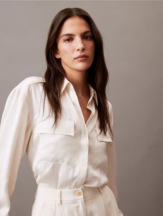 Crafted from smooth, lustrous satin, this button-down shirt appears elegant tucked into pleated pants or left untucked and slightly unbuttoned. Designed with dual chest pockets and a concealed button placket.  Material: 100% Polyester. Satin Button Down Shirt, Pleated Pants, Button Placket, Chest Pocket, Button Downs, Scoop Neck, Calvin Klein, Button Down Shirt, Cute Outfits