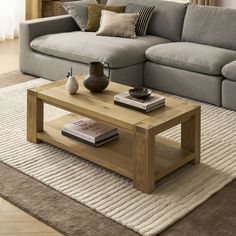 a living room with a couch, coffee table and books on the floor in front of it