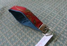 a red and blue keychain with a name tag attached to it on a bed