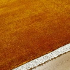 an orange and white rug with fringes on the floor in front of a wooden floor